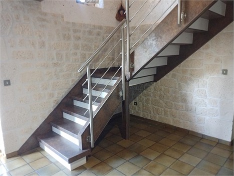 Double escalier rénové en bois clair dans une maison en pierre