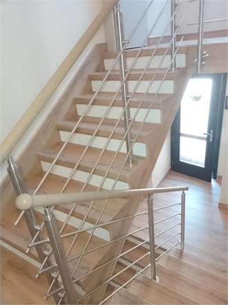 Escalier bois clair avec garde-corps inox dans une entrée lumineuse